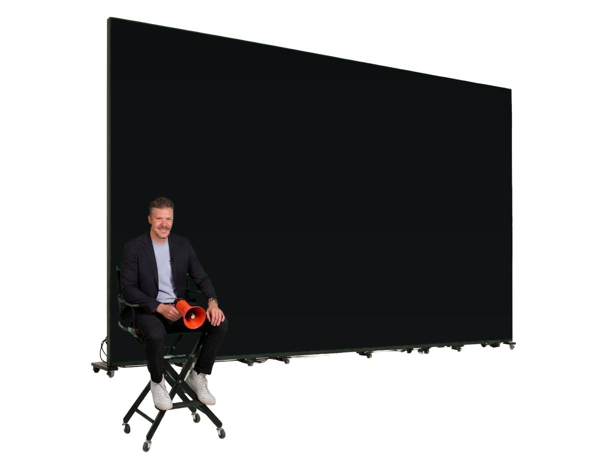 Tripp Crosby in a director's chair beside a giant studio screen